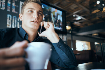 A business man in a cafe is sitting at a table while working in front of a laptop