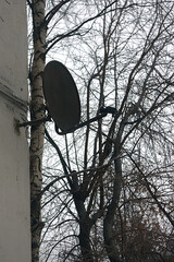 very old satellite dish on the wall of the house