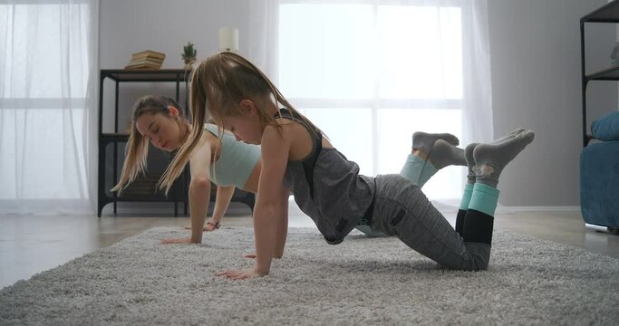 little girl and her mother are doing push-ups in living room, healthy lifestyle and physical exercise, home fitness