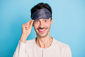 Portrait of nice cheerful funky brunet guy putting eye mask on having fun flight isolated over bright blue color background