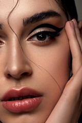 Fototapeta na wymiar Young fashion woman with evening make-up in the form of graphic arrows on her eyes. Glossy healthy skin.