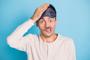 Portrait of nice funny puzzled guy wearing sleep mask oops mistake reaction isolated over bright blue color background