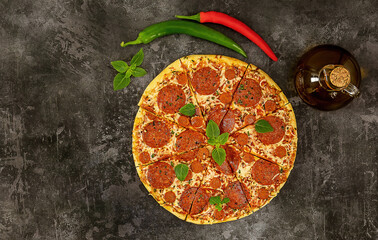 Obraz na płótnie Canvas Tasty pepperoni pizza and cooking ingredients, chili, basil on dark background.