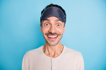 Portrait of nice cheerful amazed brunet guy wearing sleep mask having fun good mood isolated over bright blue color background