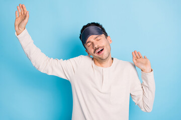 Fototapeta premium Portrait of nice healthy sleepy guy wearing sleep mask stretching yawning awakening isolated over bright blue color background