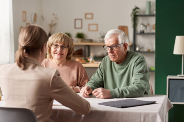 Senior couple sitting at the table with realtor and have a consultation about financial documents...
