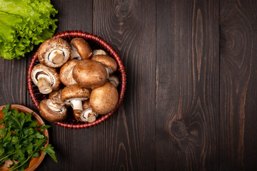 Obraz na płótnie Canvas mushrooms in a basket with lettuce and herbs on a dark wooden background topr view
