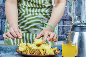 Hand holding slices of pineapple next to teapot and a glass of juice