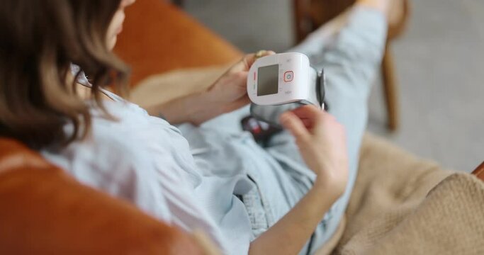 Woman measures blood pressure with wrist tonometer, calling a doctor with phone. onsultation with a therapist online and modern gadgets for health monitoring