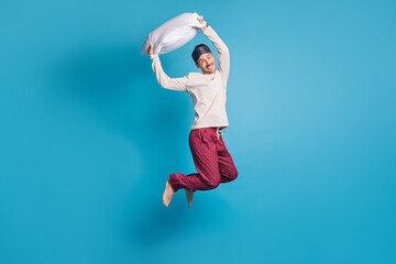 Photo portrait full body view of smiling guy ready for pillow fight jumping up isolated on vivid...