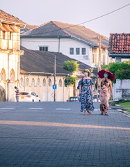 Galle, Sri Lanka - 02 12 2021: Two female tourists with big hats walks in the streets of Galle fort in the evening, enjoying the beautiful view of colonial age built city. interlock blocks street.