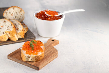 Baguette, red caviar, dill on white background with copy space. Cooking process. Recipe for making an appetizer with red caviar. Top view.