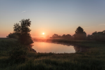 Fototapeta na wymiar Dawn over a misty lake in spring