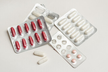 Capsules and tablets with medicine and vitamins in blisters and on a white surface, selective focus