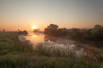 Fototapeta premium Dawn over a misty lake in spring