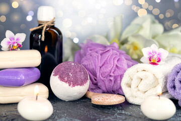 Obraz na płótnie Canvas Bath bomb, orchid flowers, burning candles, towel, massage oil, soap, washcloths, combs, abstract lights. Spa resort therapy composition.