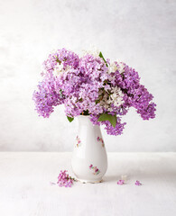 Bouquet of Lilac in old porcelain vase on a white wooden table.  Selective focus.