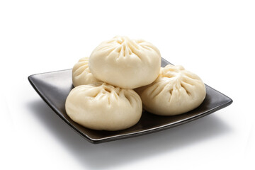Fresh baozi (Chinese steamed buns) in a black ceramics plate. Isolated on white background.