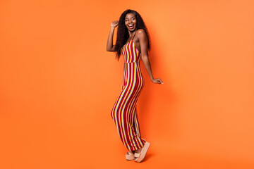 Full size profile side photo of afro american happy lady look empty space dance isolated on orange color background