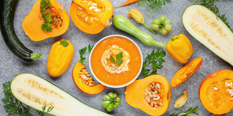 Pumpkin soup and various vegetables on a dark background. Top view.