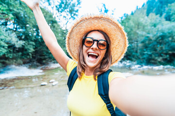 Travel blogger taking a selfie outdoors - Happy woman with backpack smiling at camera - People,...