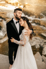 Beautiful wedding couple on the background of a waterfall and a stone river.