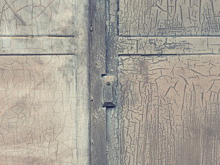 Closed industrial door locked with safetuy lock. Weathered pant on door