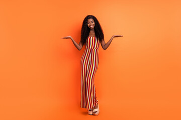 Full length photo of dark skin happy young woman hold hands copyspace present isolated on orange color background