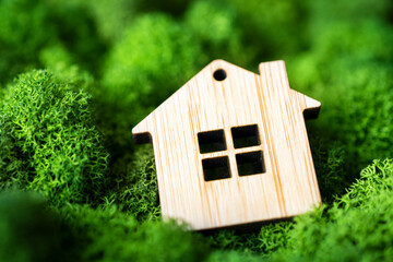 Miniature wooden house on green moss. concept of selling, insuring or renting real estate. small...