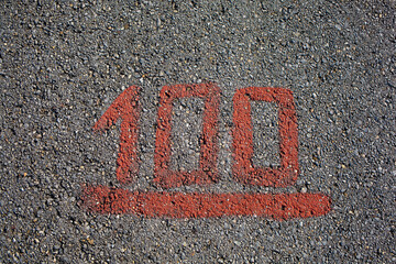 Grey asphalt road with red painted number one hundred