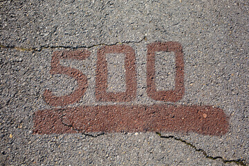 Grey asphalt road with red painted number five hundred