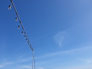 Light bulbs on string wire against the sky