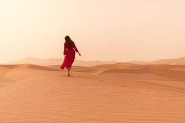 Fototapeta na wymiar A girl in a red dress in the desert