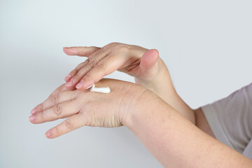 close-up of middle-aged female hand, applying a moisturizing, rejuvenating hand cream, disinfection of skin during viral epidemic, medical, cosmetology concept