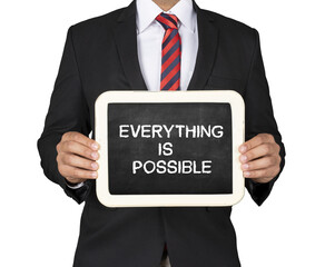A Businessman holding slate mini blackboard with message Everything is possible