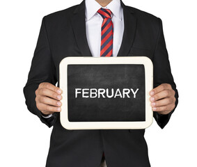 A Businessman holding slate mini blackboard with message February