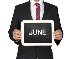 A Businessman holding slate mini blackboard with message June