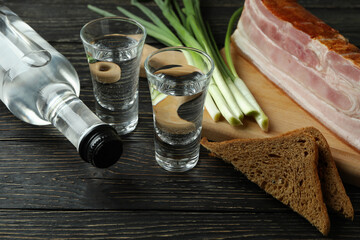 Vodka, onion, bacon and bread on wooden background