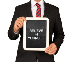 A Businessman holding slate mini blackboard with message Believe in Yourself.
