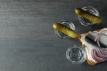 Shots of vodka and tasty snacks on dark wooden background