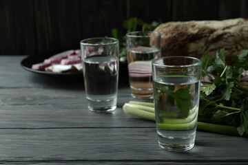 Shots of vodka and tasty snacks on wooden table, space for text