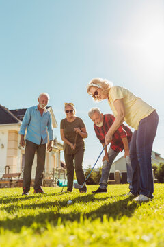 Senior Friends Playing Mini Golf At The Backyard