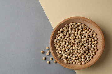 Wooden bowl with fresh chickpea on two tone background