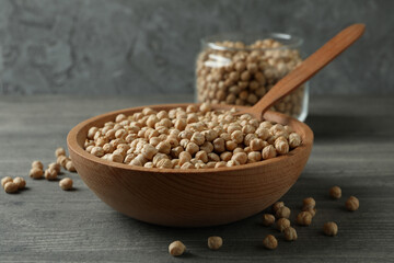 Bowl, jar and spoon with chickpea on gray table