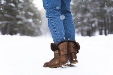 Woman wearing sheepskin boots walking by snowy road