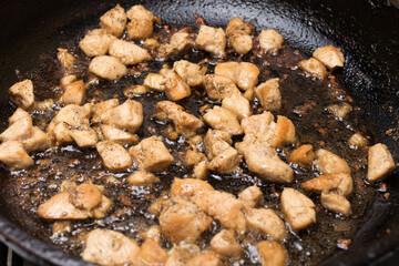 Pieces of chicken fillet are fried in a frying pan in hot vegetable oil. Cooking meat.