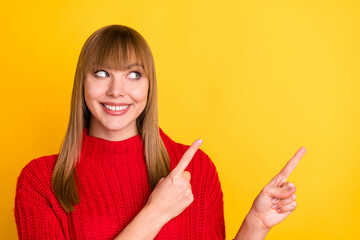 Photo of blond optimistic lady look point empty space wear red sweater isolated on bright yellow...