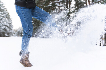 Woman wearing sheepskin boots is kicking snow