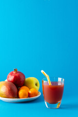 Delicious sweet mango and pomegranate juices in glass and ripe fruits on a blue background