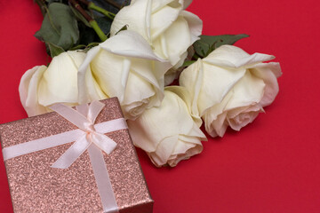 Postcard. White roses on a blue background with a pink gift box. Congratulations on March 8, Valentine's Day, Mother's Day, Birthday, Anniversary, Easter, Wedding, Teacher's Day, to women.